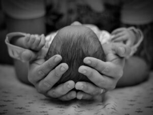 Hands Holding Head of Newborn